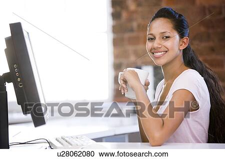 Businesswoman in office drinking coffee and smiling View Large Photo Image Stock Image - Businesswoman in office drinking coffee and smiling. Fotosearch