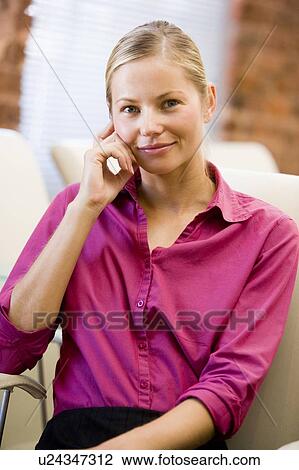 Stock Image - Businesswoman sitting in office space smiling. Fotosearch