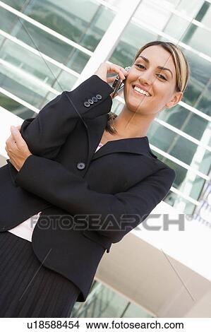 Picture - Businesswoman standing outdoors on cellular phone smiling. Fotosearch