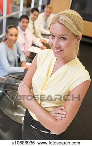 Stock Photograph - Businesswoman with four businesspeople at boardroom table in background. Fotosearch