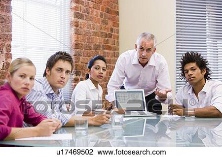Stock Image - Five businesspeople in boardroom with laptop. Fotosearch