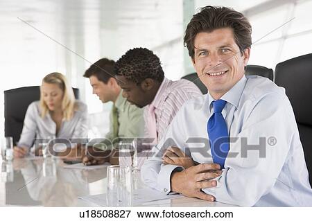 Stock Photo - Four businesspeople in a boardroom smiling. Fotosearch