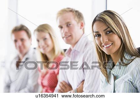 Stock Image - Four businesspeople sitting indoors smiling. Fotosearch