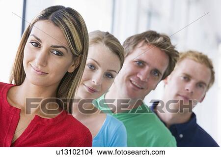 Four people standing in corridor smiling View Large Photo Image Picture - Four people standing in corridor smiling. Fotosearch