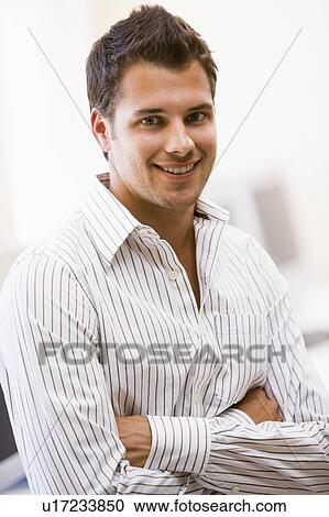 Stock Image - Man standing in computer room smiling. Fotosearch