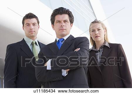 Three businesspeople standing outdoors by building View Large Photo Image Picture - Three businesspeople standing outdoors by building. Fotosearch