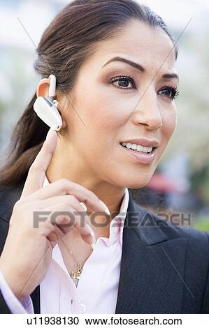Stock Image - Woman wearing headset outdoors smiling (selective focus). Fotosearch
