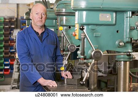Stock Image - Machinist working on machine. Fotosearch