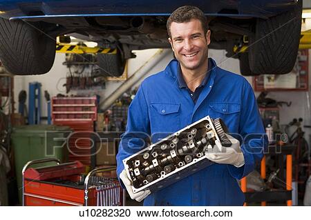 Mechanic holding car part smiling View Large Photo Image Stock Image - Mechanic holding car part smiling. Fotosearch