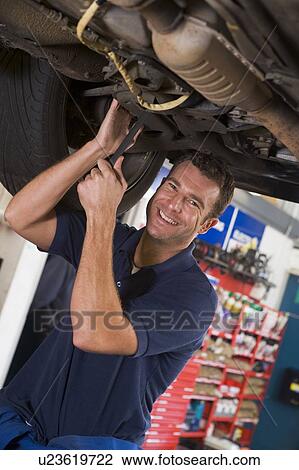 Mechanic working under car smiling View Large Photo Image Stock Image - Mechanic working under car smiling. Fotosearch