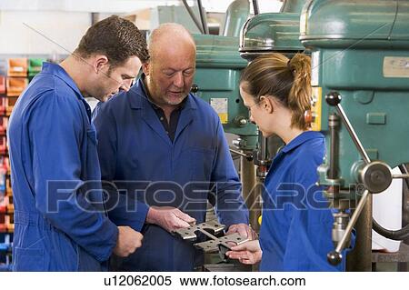 Three machinists in workspace by machine talking View Large Photo Image Stock Photography - Three machinists in workspace by machine talking. Fotosearch