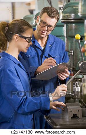 Stock Image - Two machinists working on machine. Fotosearch