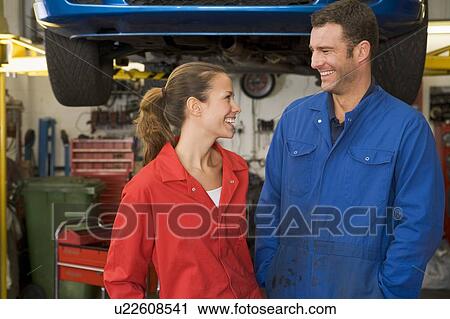 Two mechanics standing in garage smiling View Large Photo Image Stock Image - Two mechanics standing in garage smiling. Fotosearch
