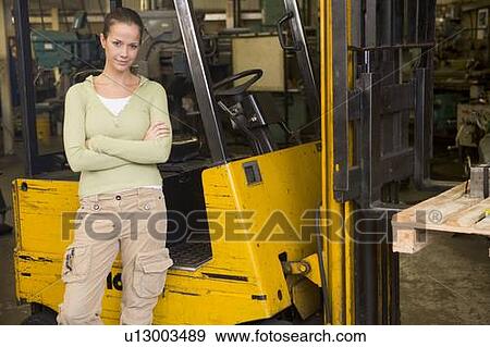 Warehouse worker standing by forklift View Large Photo Image Stock Photo - Warehouse worker standing by forklift. Fotosearch