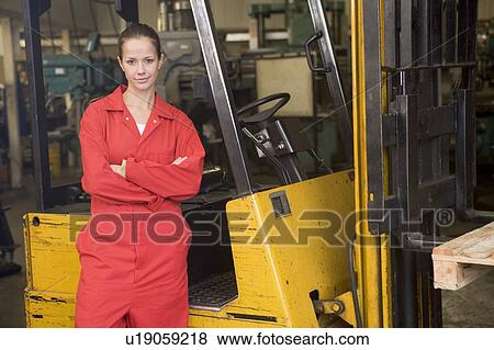 Warehouse worker standing by forklift View Large Photo Image Stock Photo - Warehouse worker standing by forklift. Fotosearch