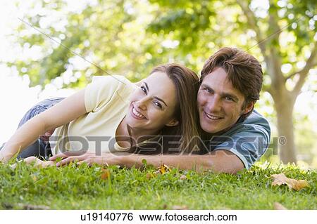 Stock Photograph - Couple lying outdoors smiling. Fotosearch