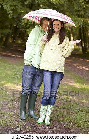 Couple outdoors in rain with umbrella smiling View Large Photo Image Stock Photography - Couple outdoors in rain with umbrella smiling. Fotosearch