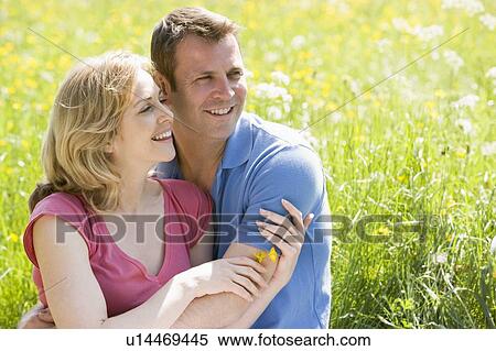 Couple sitting outdoors holding flower smiling View Large Photo Image Stock Photography - Couple sitting outdoors holding flower smiling. Fotosearch