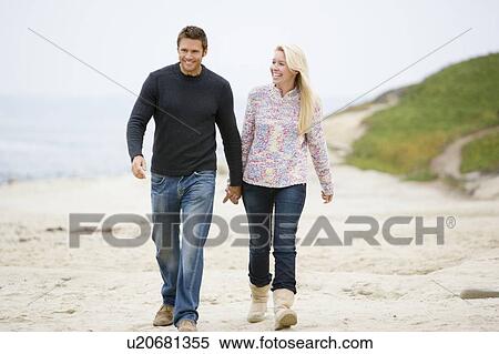 Couple walking at beach holding hands smiling View Large Photo Image Stock Photography - Couple walking at beach holding hands smiling. Fotosearch
