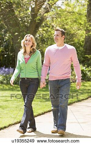 Couple walking on path holding hands smiling View Large Photo Image Stock Photo - Couple walking on path holding hands smiling. Fotosearch