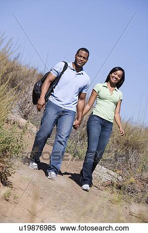 Stock Photography - Couple walking on path holding hands and smiling. Fotosearch