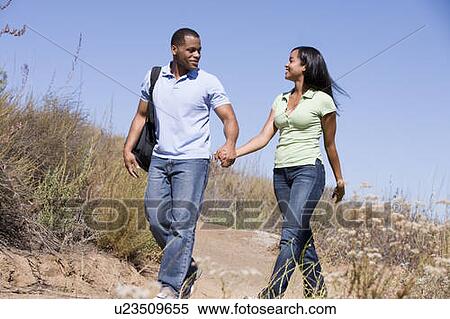 Couple walking on path holding hands and smiling View Large Photo Image Stock Photography - Couple walking on path holding hands and smiling. Fotosearch