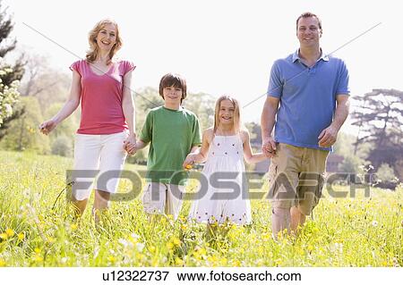 Stock Photo - Family walking outdoors holding flower smiling. Fotosearch