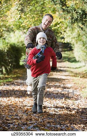 Picture - Grandfather and grandson running outdoors in park and smiling. Fotosearch