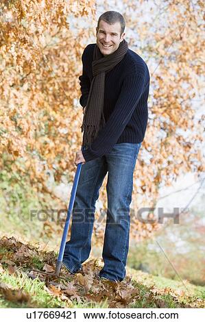 Man outdoors raking leaves and smiling (selective focus) View Large Photo Image Stock Image - Man outdoors raking leaves and smiling (selective focus). Fotosearch