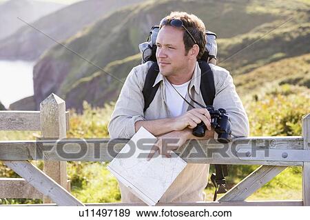 Man relaxing on cliffside path holding map and binoculars View Large Photo Image Stock Photo - Man relaxing on cliffside path holding map and binoculars. Fotosearch