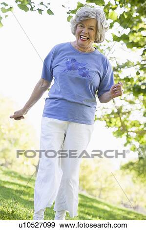 Senior woman walking in park View Large Photo Image Stock Photo - Senior woman walking in park. Fotosearch