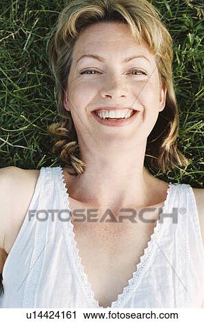 Stock Image - Woman lying outdoors smiling. Fotosearch