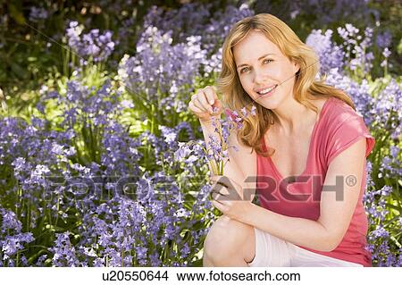 Picture - Woman outdoors holding flowers smiling. Fotosearch