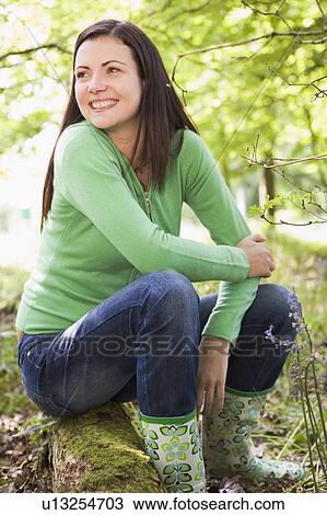 Woman outdoors in woods sitting on log smiling View Large Photo Image Stock Image - Woman outdoors in woods sitting on log smiling. Fotosearch