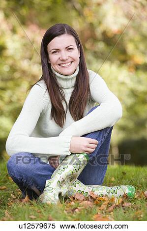 Woman sitting outdoors smiling (selective focus) View Large Photo Image Stock Photography - Woman sitting outdoors smiling (selective focus). Fotosearch