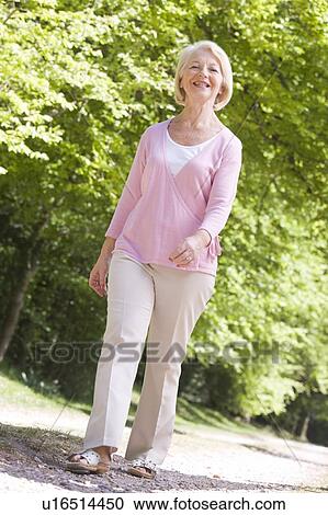 Stock Image - Woman walking outdoors smiling. Fotosearch