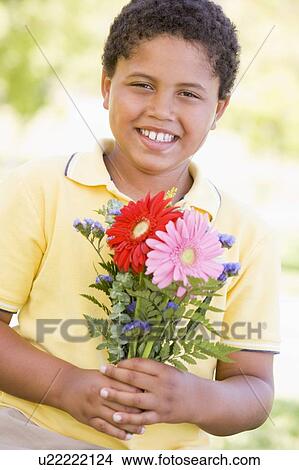 Picture - Young boy holding flowers and smiling. Fotosearch