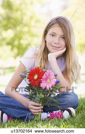 Young girl holding flowers and smiling View Large Photo Image Picture - Young girl holding flowers and smiling. Fotosearch