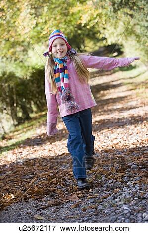 Stock Photo - Young girl outdoors at park running on path smiling (selective focus). Fotosearch