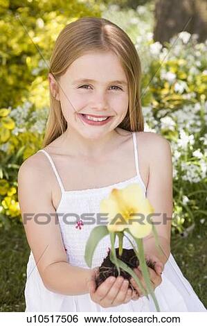 Young girl outdoors holding flower smiling View Large Photo Image Stock Photograph - Young girl outdoors holding flower smiling. Fotosearch