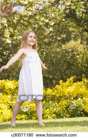 Stock Image - Young girl standing outdoors smiling. Fotosearch