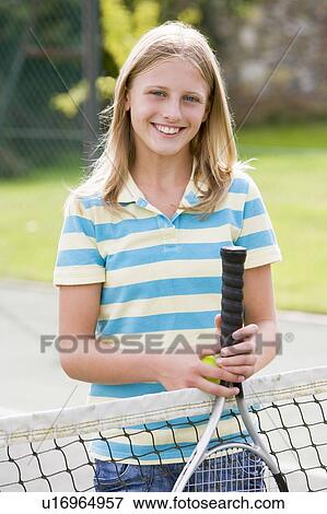 Young girl with racket on tennis court smiling View Large Photo Image Stock Photo - Young girl with racket on tennis court smiling. Fotosearch