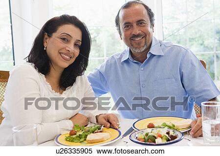 Couple sitting at dinner table smiling (high key) View Large Photo Image Stock Photography - Couple sitting at dinner table smiling (high key). Fotosearch