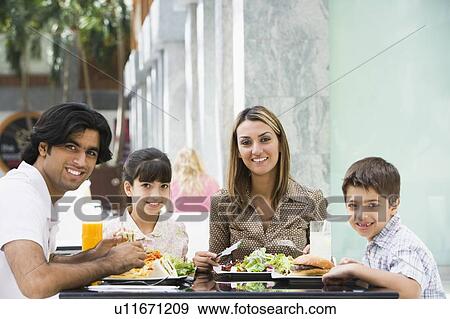 Family at restaurant eating and smiling (selective focus) View Large Photo Image Stock Photo - Family at restaurant eating and smiling (selective focus). Fotosearch