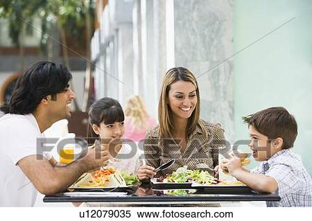 Family at restaurant eating and smiling (selective focus) View Large Photo Image Stock Photography - Family at restaurant eating and smiling (selective focus). Fotosearch