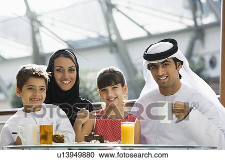 Stock Image - Family at restaurant eating dessert and smiling (selective focus). Fotosearch