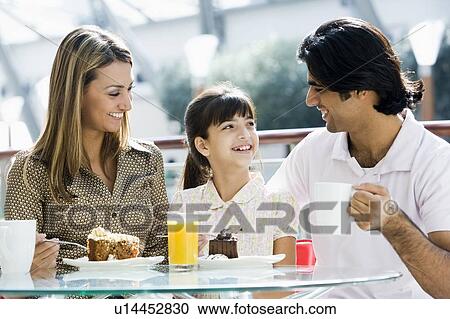 Stock Image - Family at restaurant eating dessert and smiling (selective focus). Fotosearch