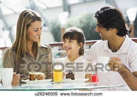 Family at restaurant eating dessert and smiling (selective focus) View Large Photo Image Stock Photo - Family at restaurant eating dessert and smiling (selective focus). Fotosearch