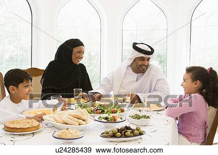Family sitting at dinner table smiling (high key) View Large Photo Image Stock Photo - Family sitting at dinner table smiling (high key). Fotosearch