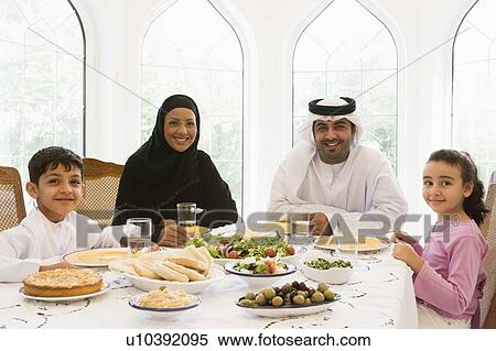 Stock Photography - Family sitting at dinner table smiling (high key). Fotosearch